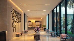 A modern lobby with a chandelier, seating area, and a large window with a view of greenery. - Taj Surajkund Resort & Spa, Delhi NCR (Faridabad)
