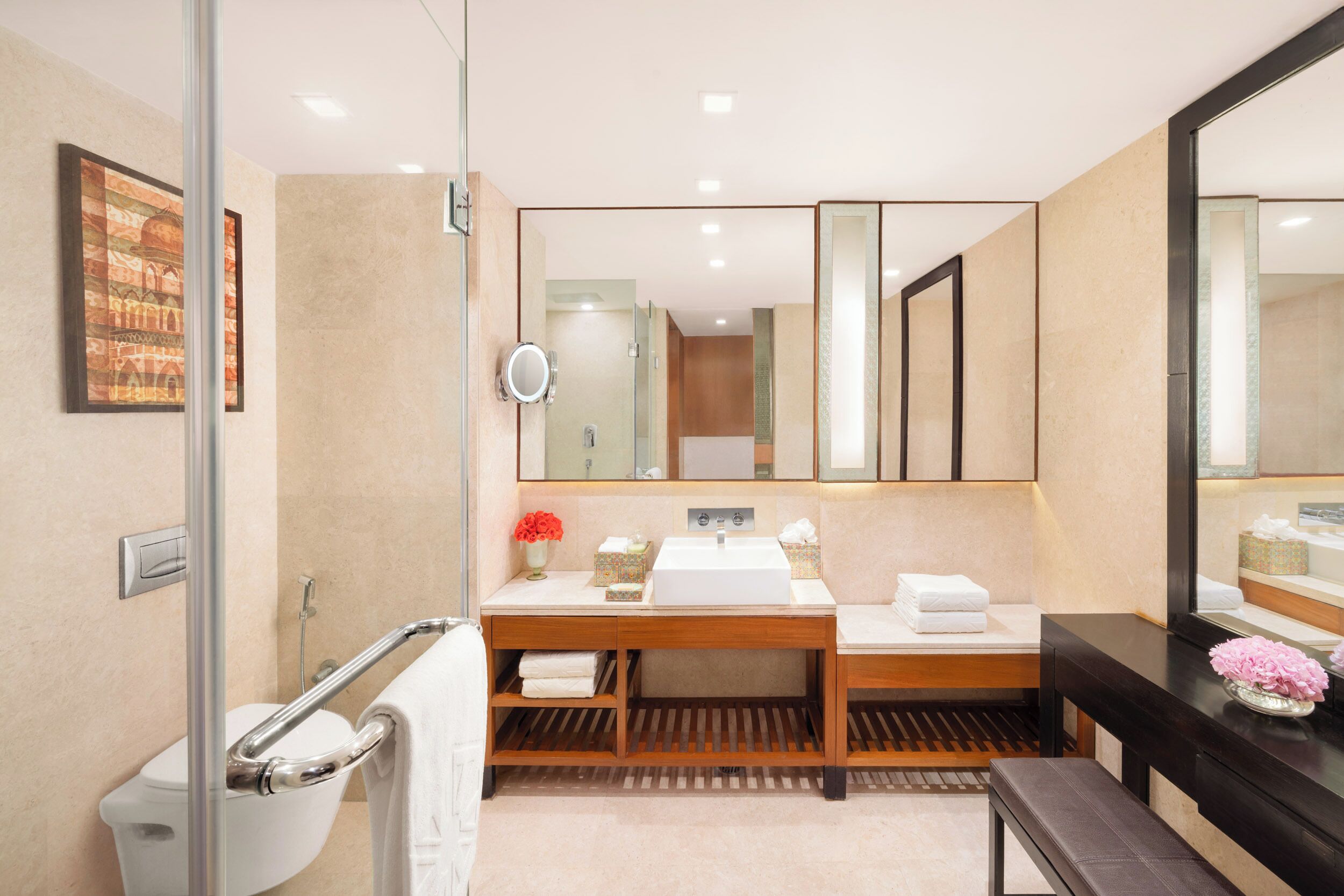 Un baño moderno con cabina de ducha de vidrio, un lavabo blanco, un espejo grande y un mueble de tocador de madera.