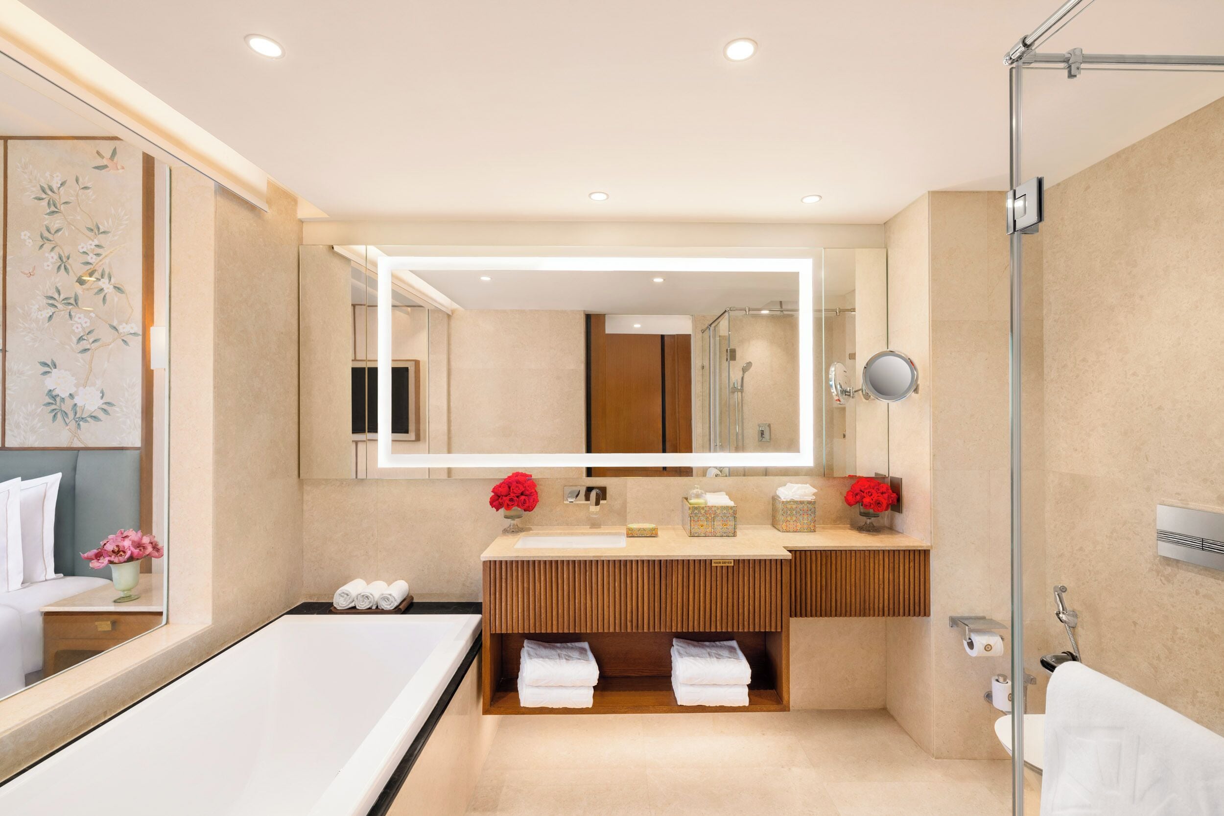 A modern bathroom with a large mirror, a bathtub, and a shower area.