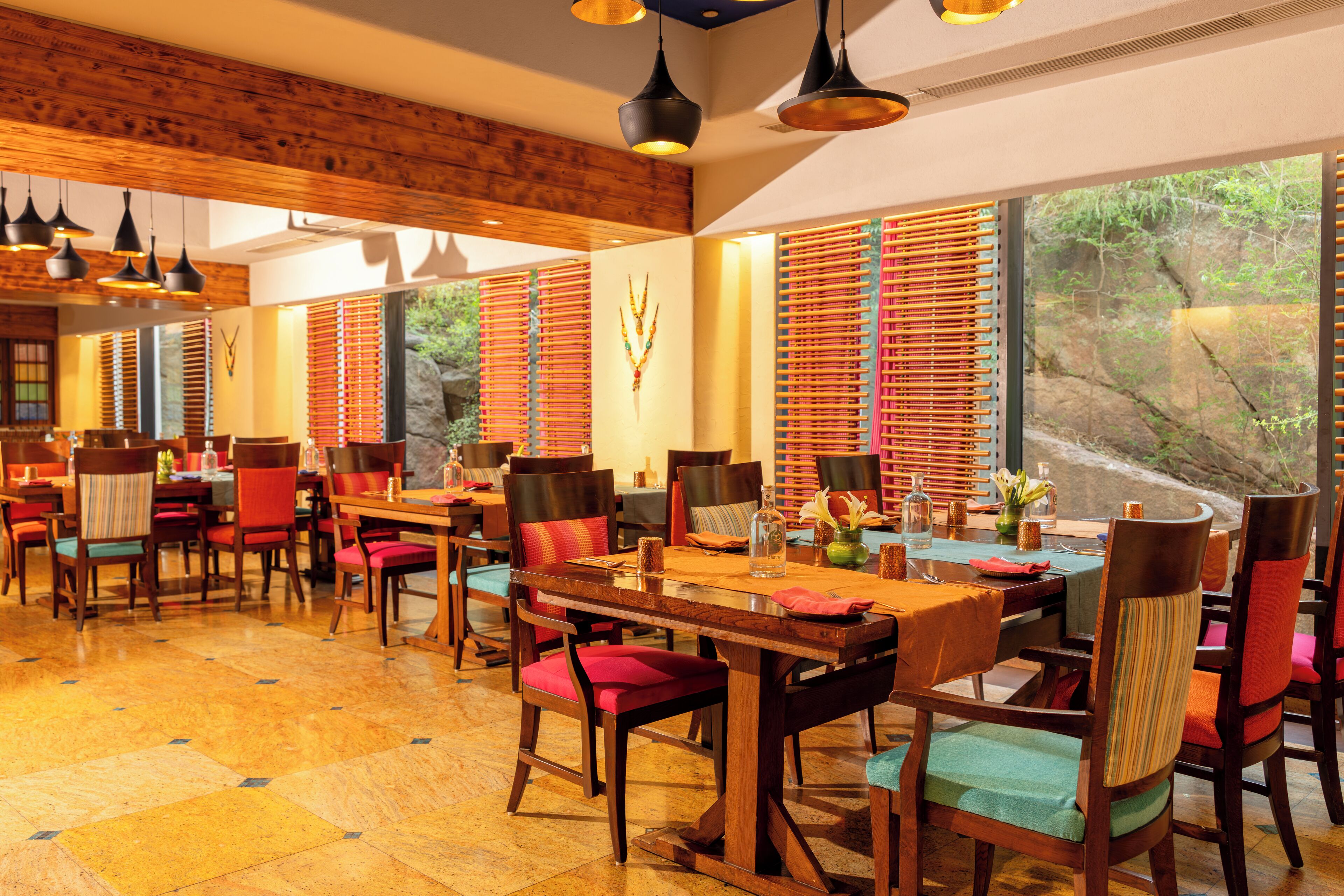 Un restaurante con paredes de madera, ventanas amplias y varias mesas con sillas.