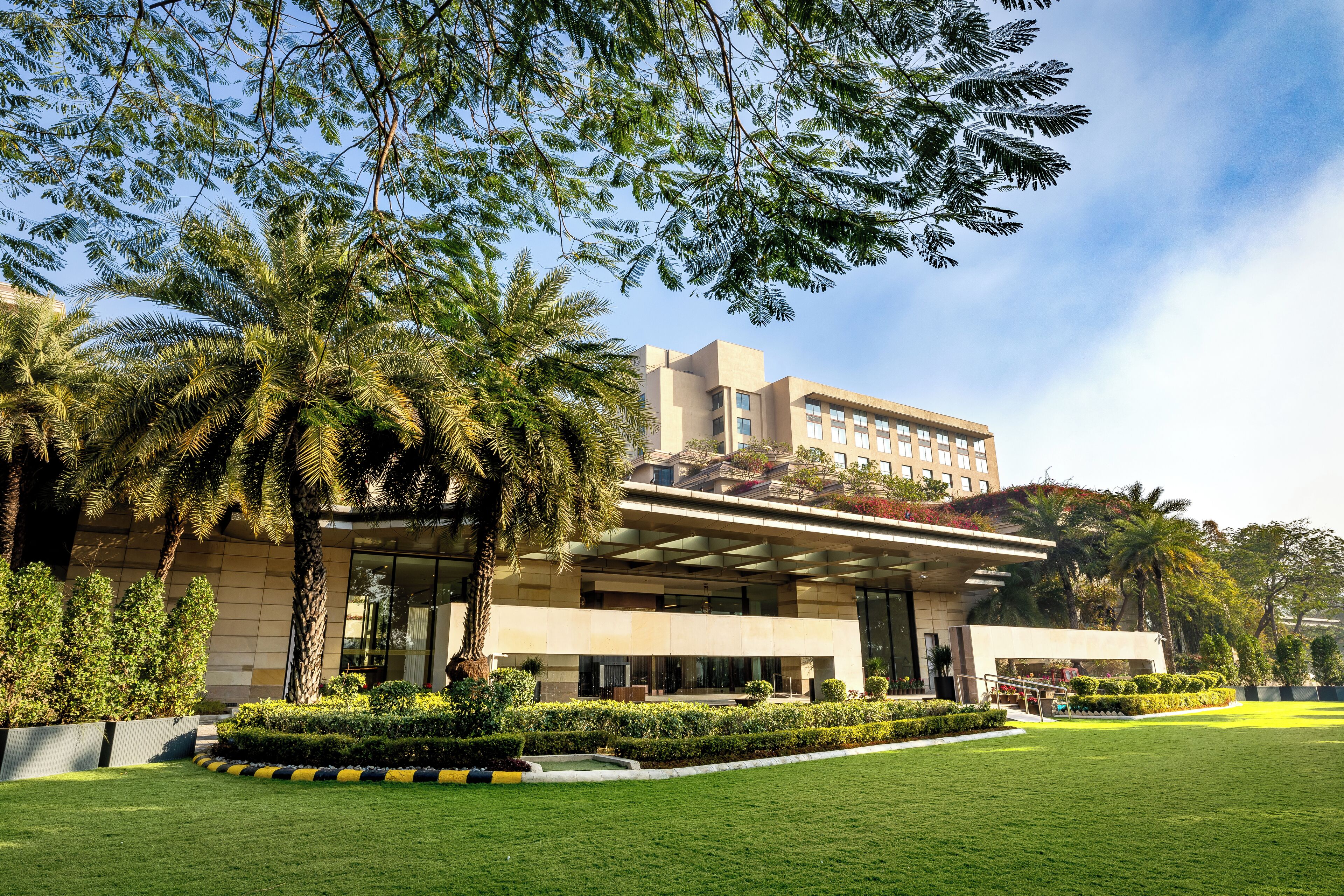 A modern hotel with a flat roof, large windows, and a well-maintained lawn.