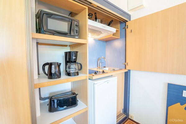 A compact kitchenette with a microwave, coffee maker, toaster, and a small refrigerator.