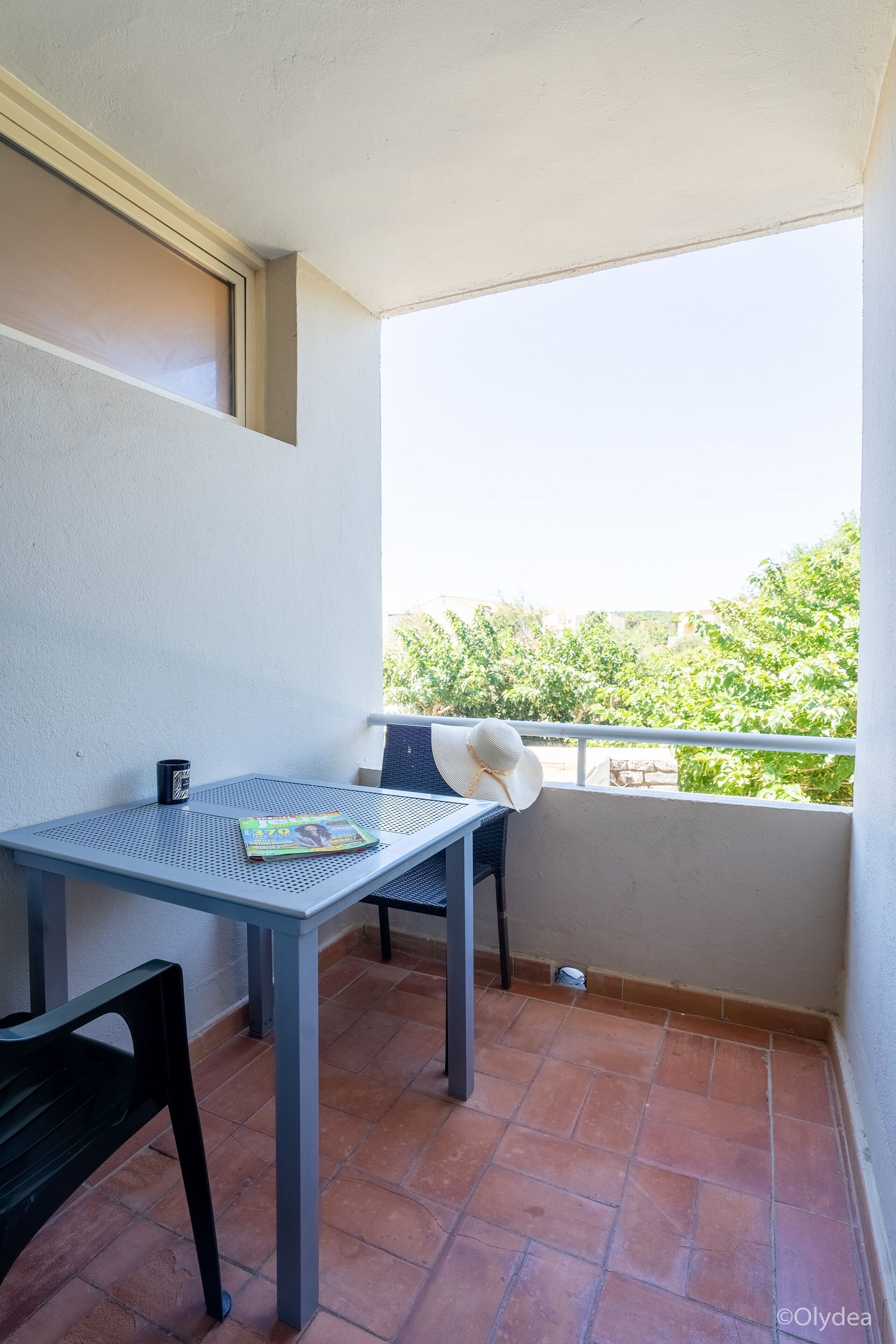 A small balcony with a table, chairs, and a magazine.