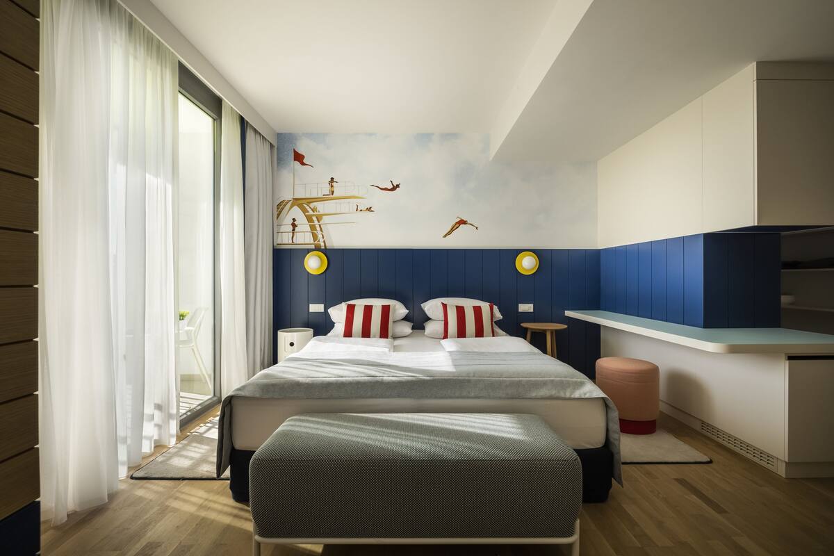 Ein modernes Schlafzimmer mit einem großen Bett, einem Schreibtisch und einem Fenster mit Vorhängen.