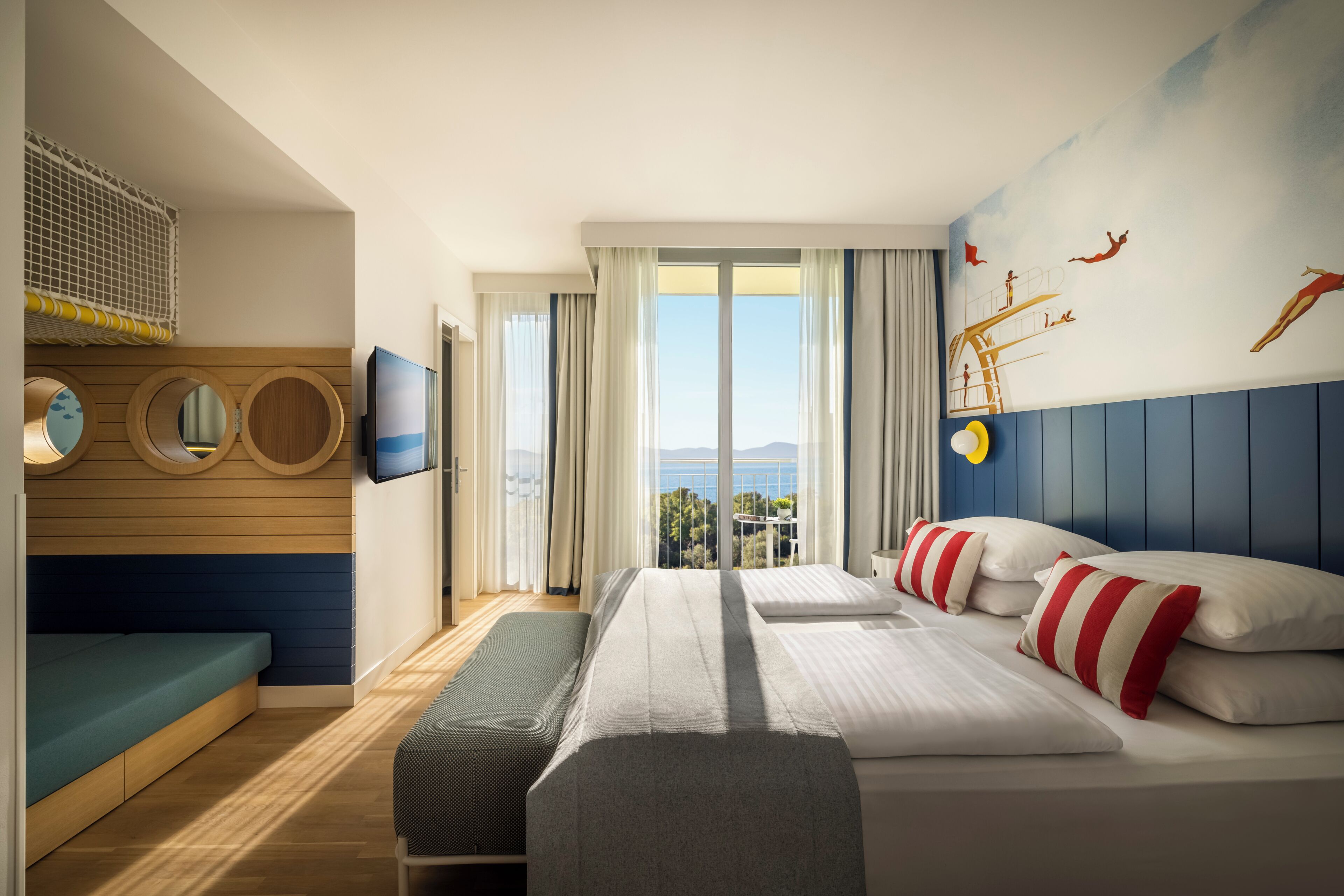 A hotel room with a bed, a bench, a TV, a window with curtains, and a mural on the wall.