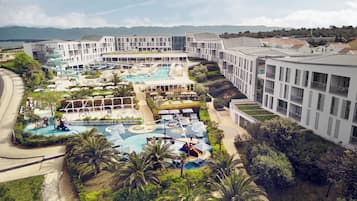 Relax by the large outdoor pool surrounded by lush greenery and palm trees.