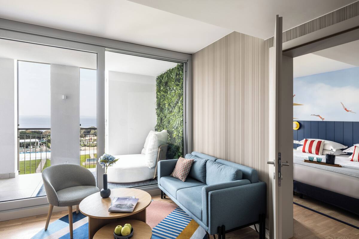 Ein modernes Wohnzimmer mit einer Couch, einem Sessel, einem Couchtisch und Blick auf den Ozean durch große Fenster.