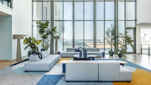 A spacious living area with a large window, modern furniture, and potted plants. - Falkensteiner Family Hotel Diadora (Zadar)