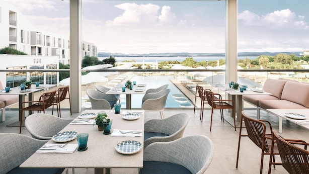 A rooftop dining area with tables, chairs, and a pool view. - Falkensteiner Family Hotel Diadora (Zadar)