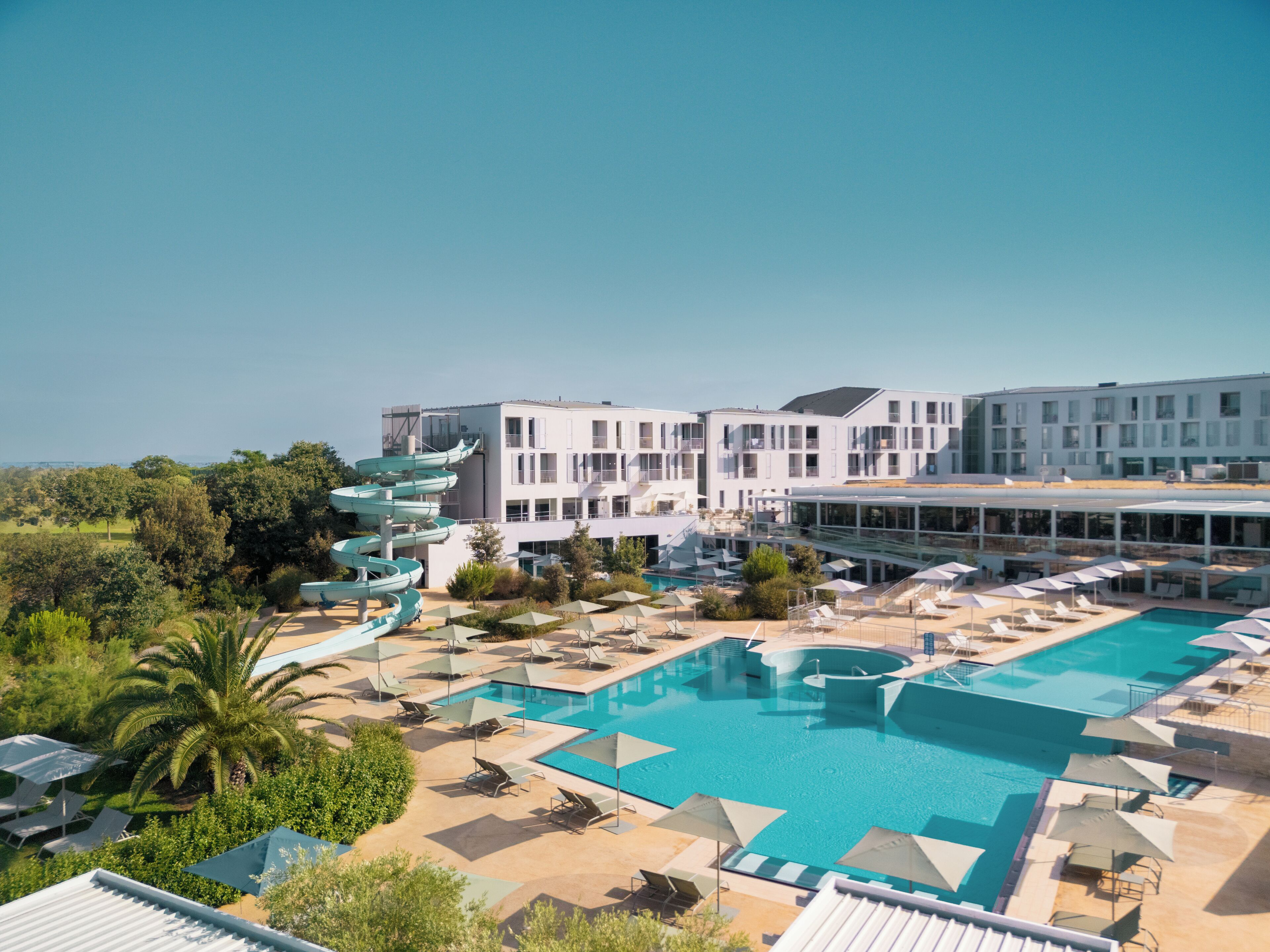 A resort with a large pool area, multiple swimming pools, and a modern building with balconies.