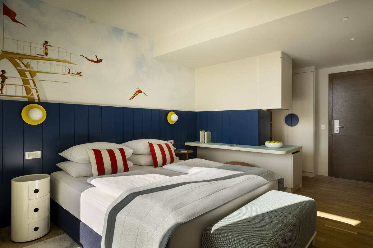 Ein modernes Schlafzimmer mit einem Bett, einem Nachttisch, einer Kommode und einer Wandmalerei.