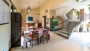 Un comedor amplio con una larga mesa dispuesta para varios invitados, una escalera que conduce a un nivel superior y vistas al exterior.