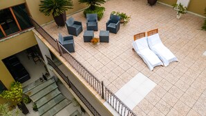Un patio al aire libre con asientos, una cama y plantas en macetas.