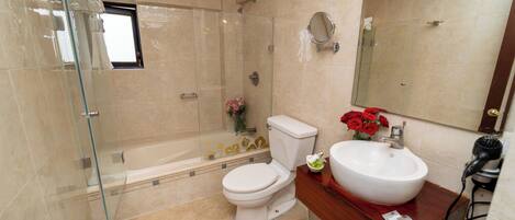 A modern bathroom with a glass-enclosed shower, a white toilet, a vanity with a sink, and a hairdryer.