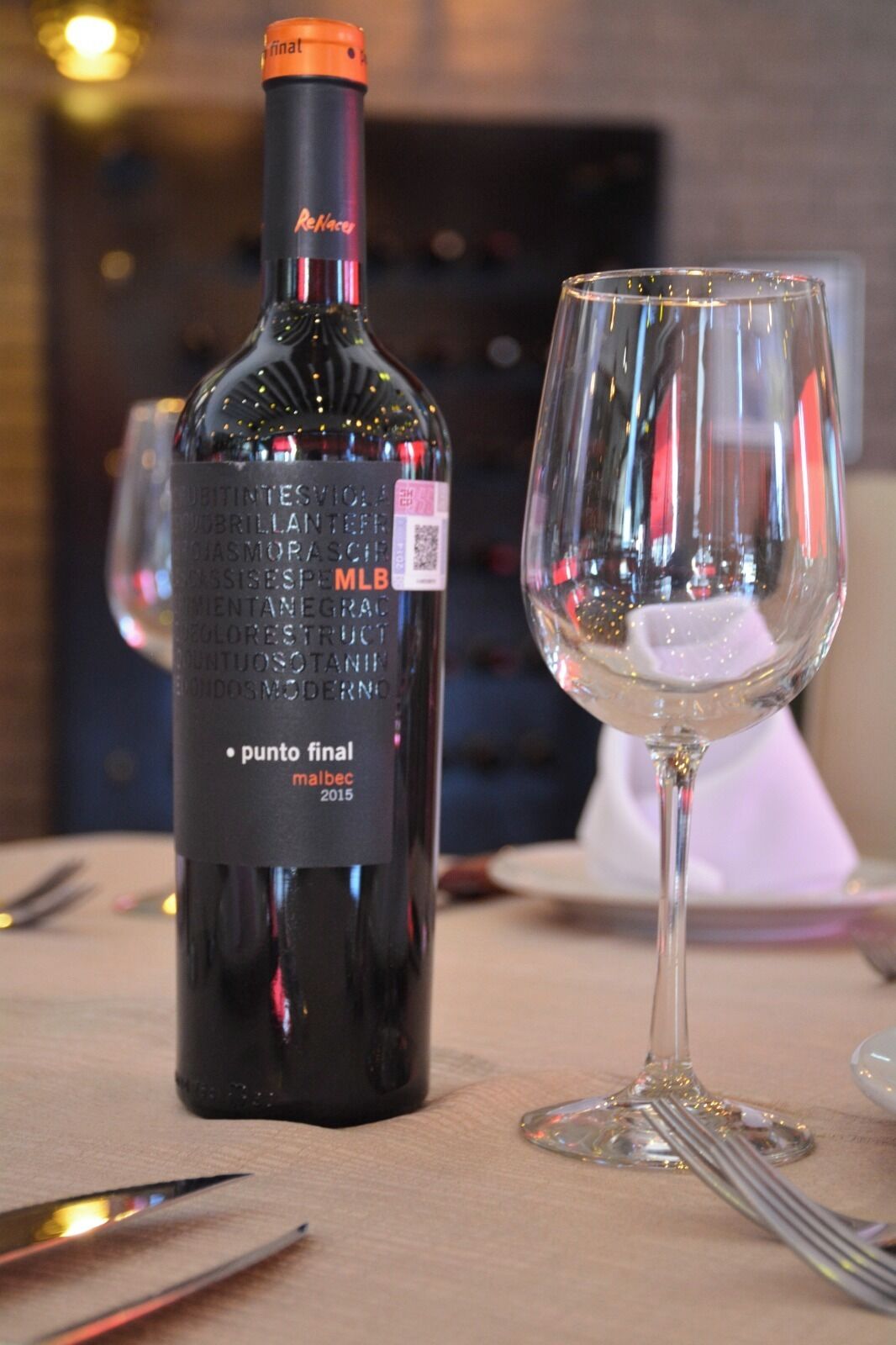 A bottle of wine and an empty wine glass on a table.