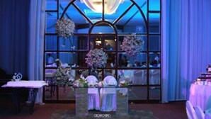 Un espace d’accueil avec une cloison en verre, des compositions florales et un lustre.