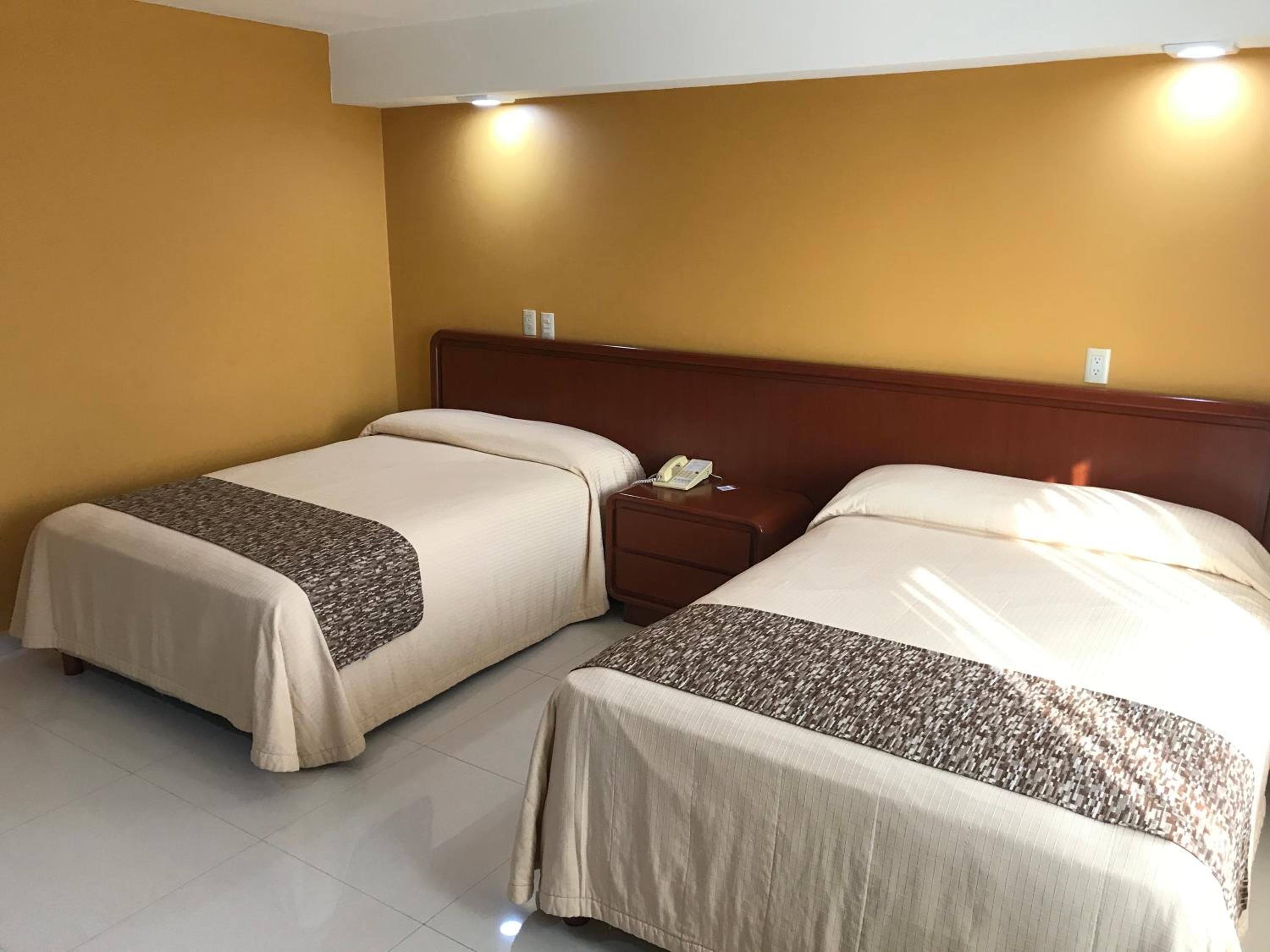 A hotel room with two beds, a nightstand, and a telephone.