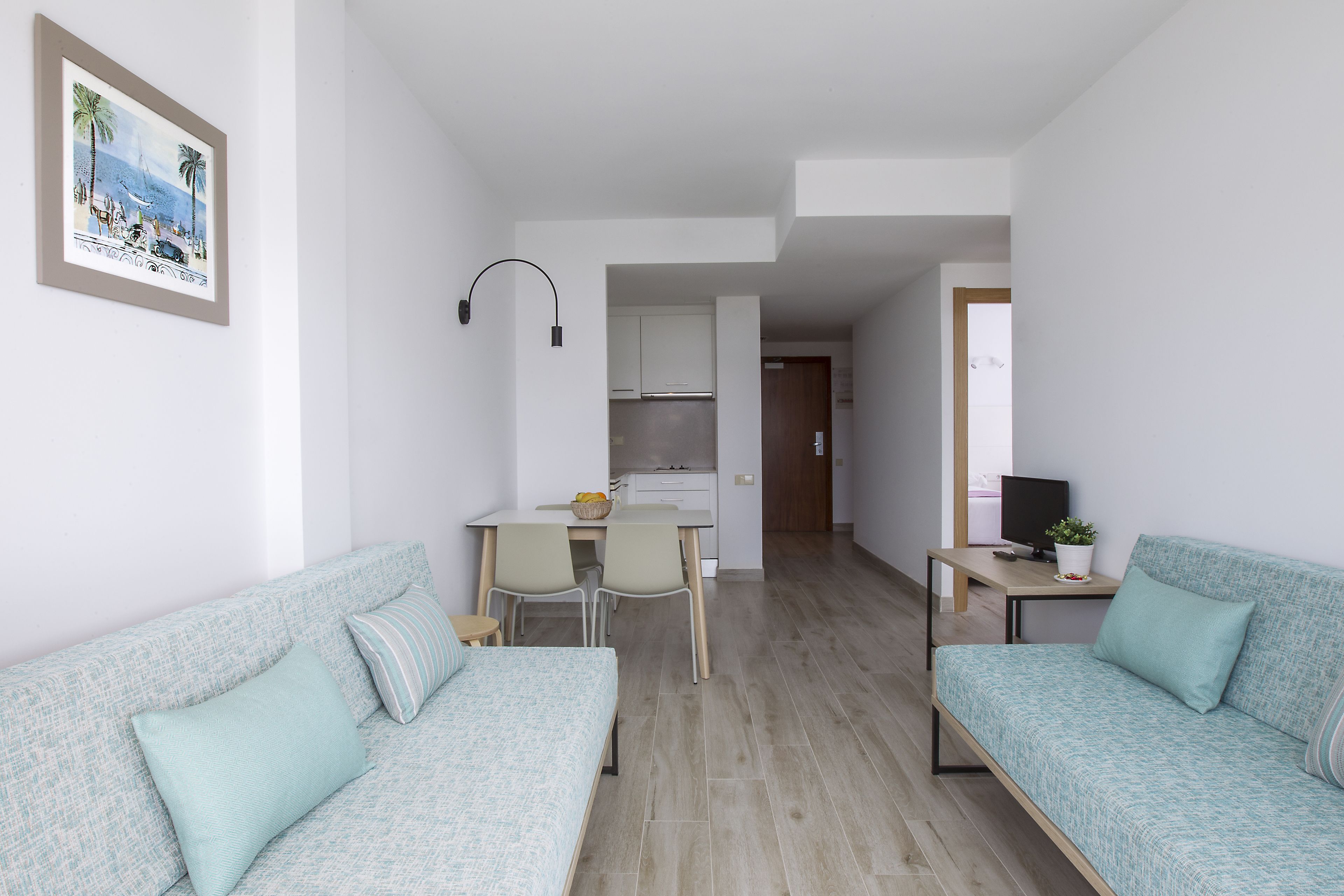 Un salon moderne avec deux canapés, un coin repas et une cuisine en arrière-plan.