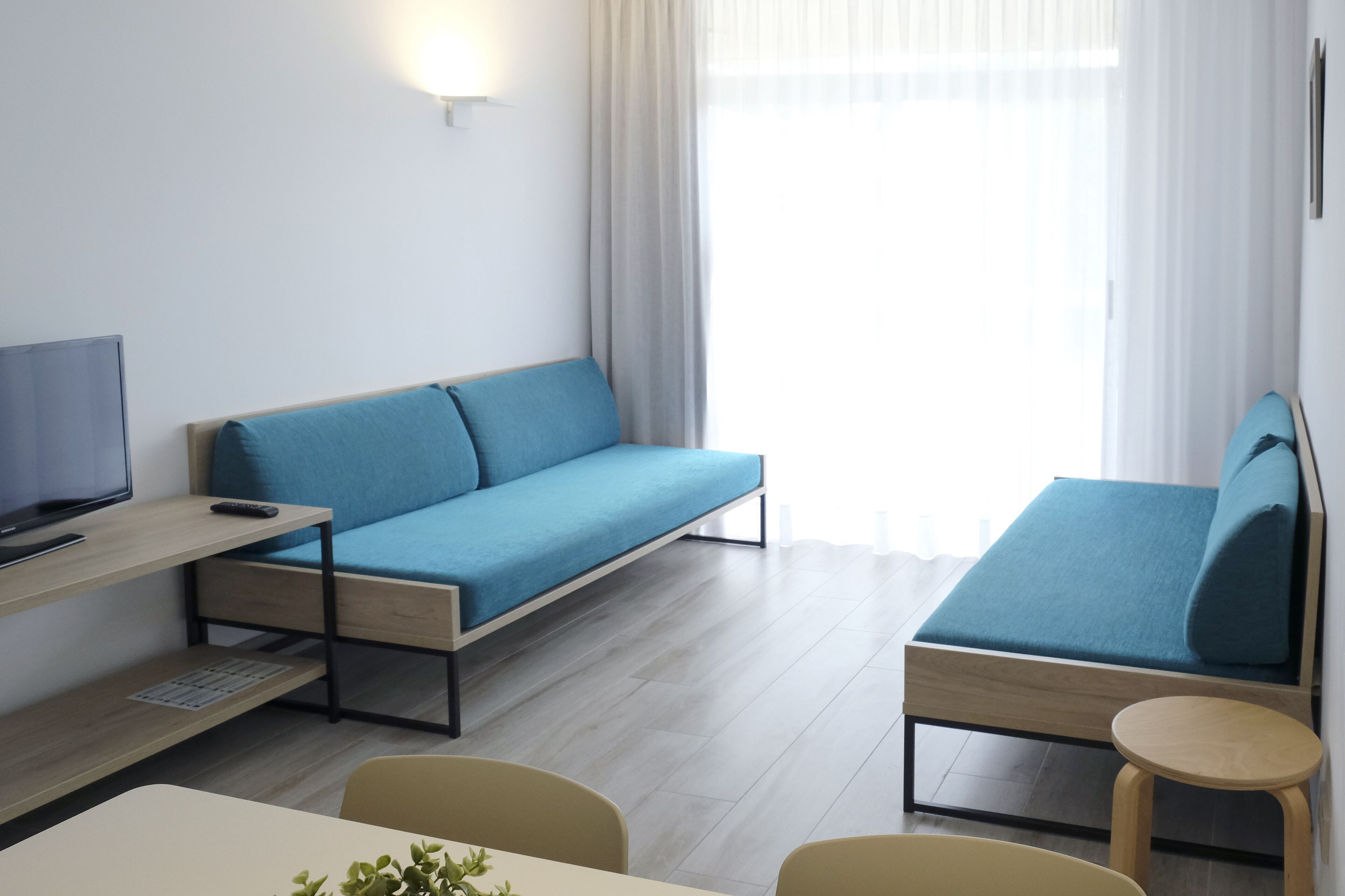 Une chambre moderne avec un canapé, une petite table et un téléviseur.