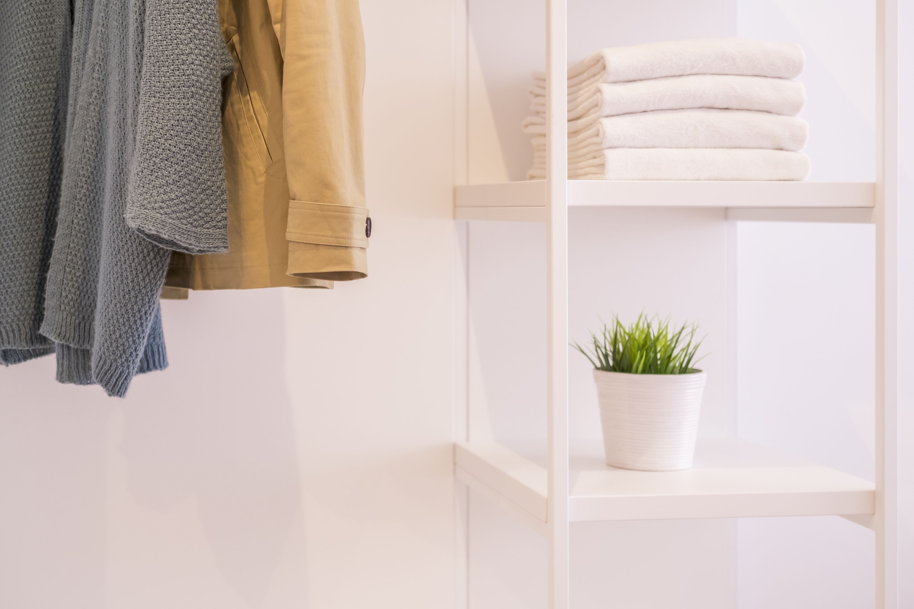 Une étagère blanche avec des serviettes pliées et une plante en pot.