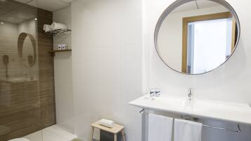 Une salle de bain moderne comprenant des toilettes, un espace douche, un lavabo avec un miroir et un petit marchepied.