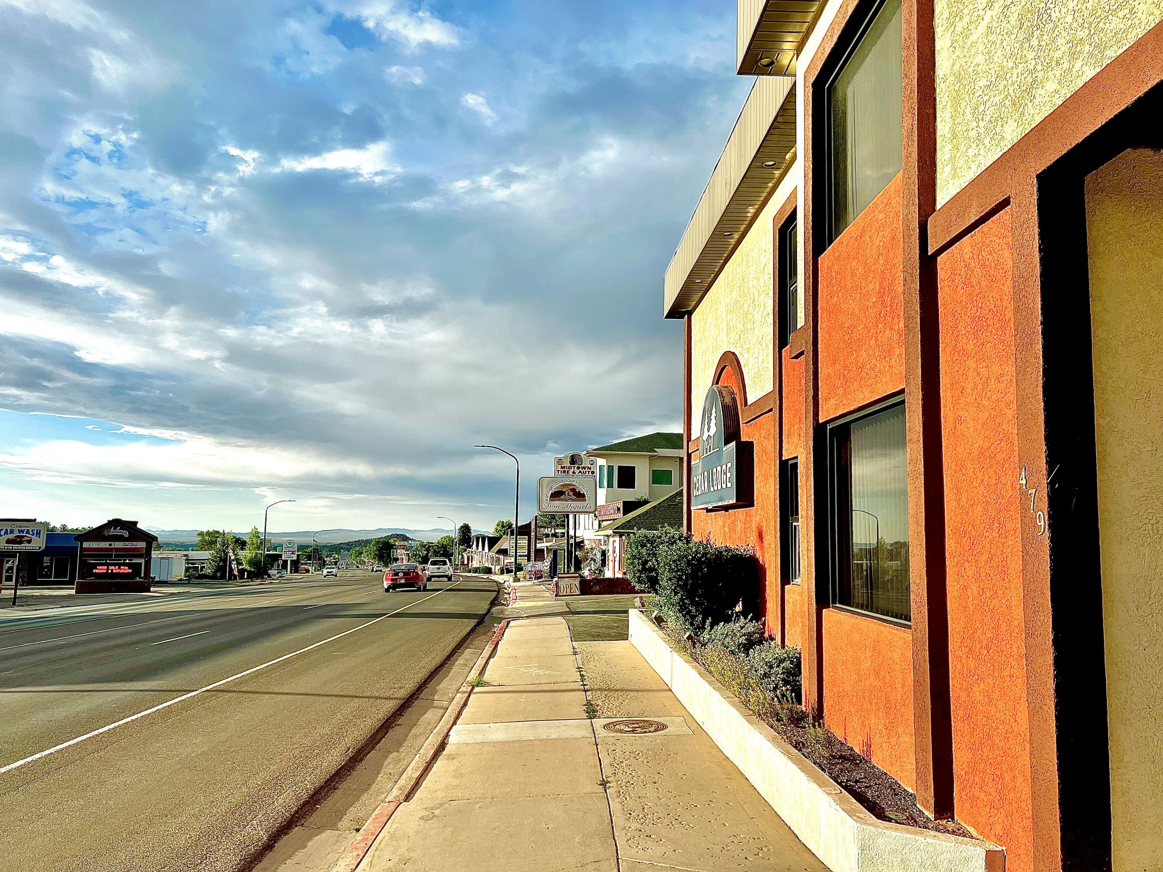 A building with a sign for 'The Cedar Lodge' and a street in front.