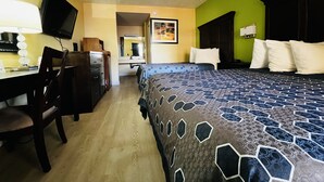 Ein Hotelzimmer mit Bett, Schreibtisch, Stuhl und Fernseher.