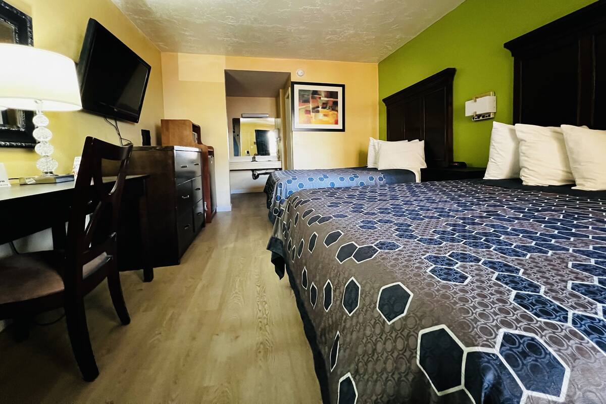 A hotel room with a bed, desk, chair, and a television.