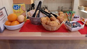 A breakfast buffet with bread, pastries, and fruit. - Hôtel Le Petit Château (Cannes)