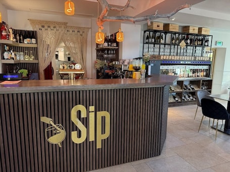 A bar area with a counter labeled 'Sip,' shelves with bottles, and a wine rack.. Old Mill Comfort