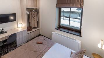 Habitación de hotel con cama, escritorio, televisor, perchero y ventana con vista al mar.