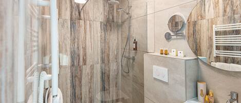 A modern bathroom with a glass-enclosed shower, a white sink, and a marble backsplash.