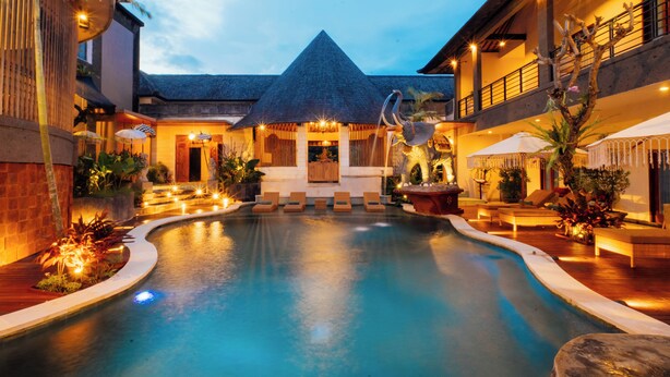 A pool area with lounge chairs, a thatched-roof building, and outdoor lighting. - The Bidadari Villas & Spa Umalas, between Seminyak and Canggu (Kerobokan)