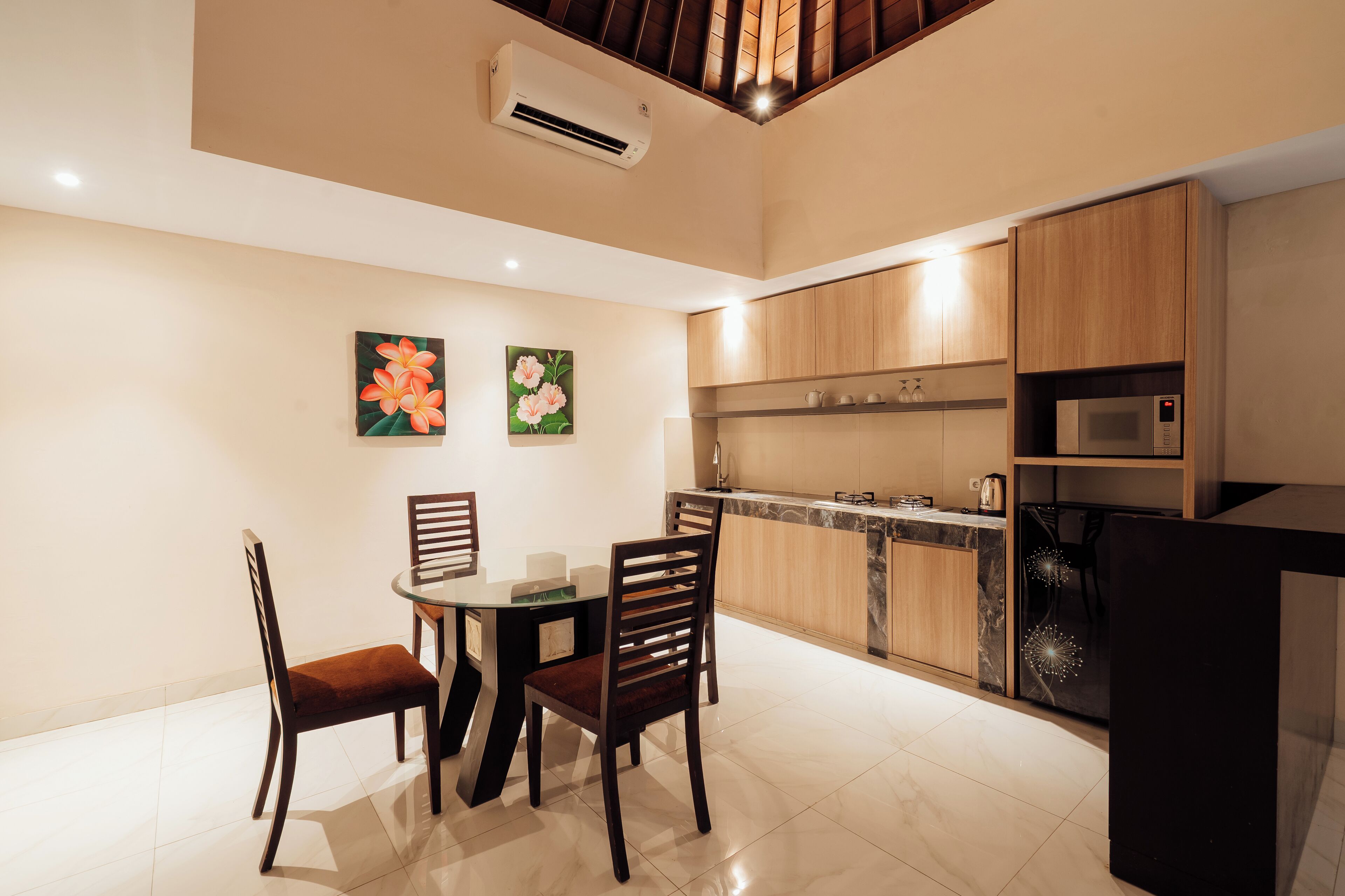 A modern kitchen with wooden cabinets, a built-in microwave, and a dining area with two chairs and a table.