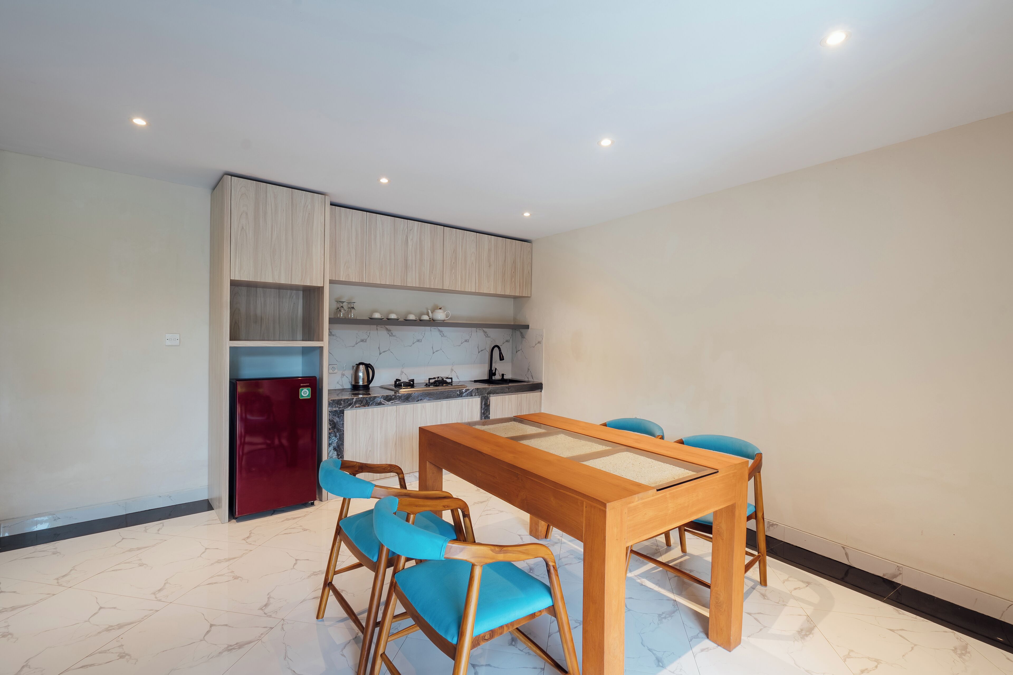 A modern kitchen with a built-in refrigerator, a dining table with chairs, and a marble floor.