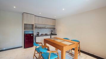 Una cocina moderna con un refrigerador empotrado, una mesa de comedor con sillas y piso de mármol.