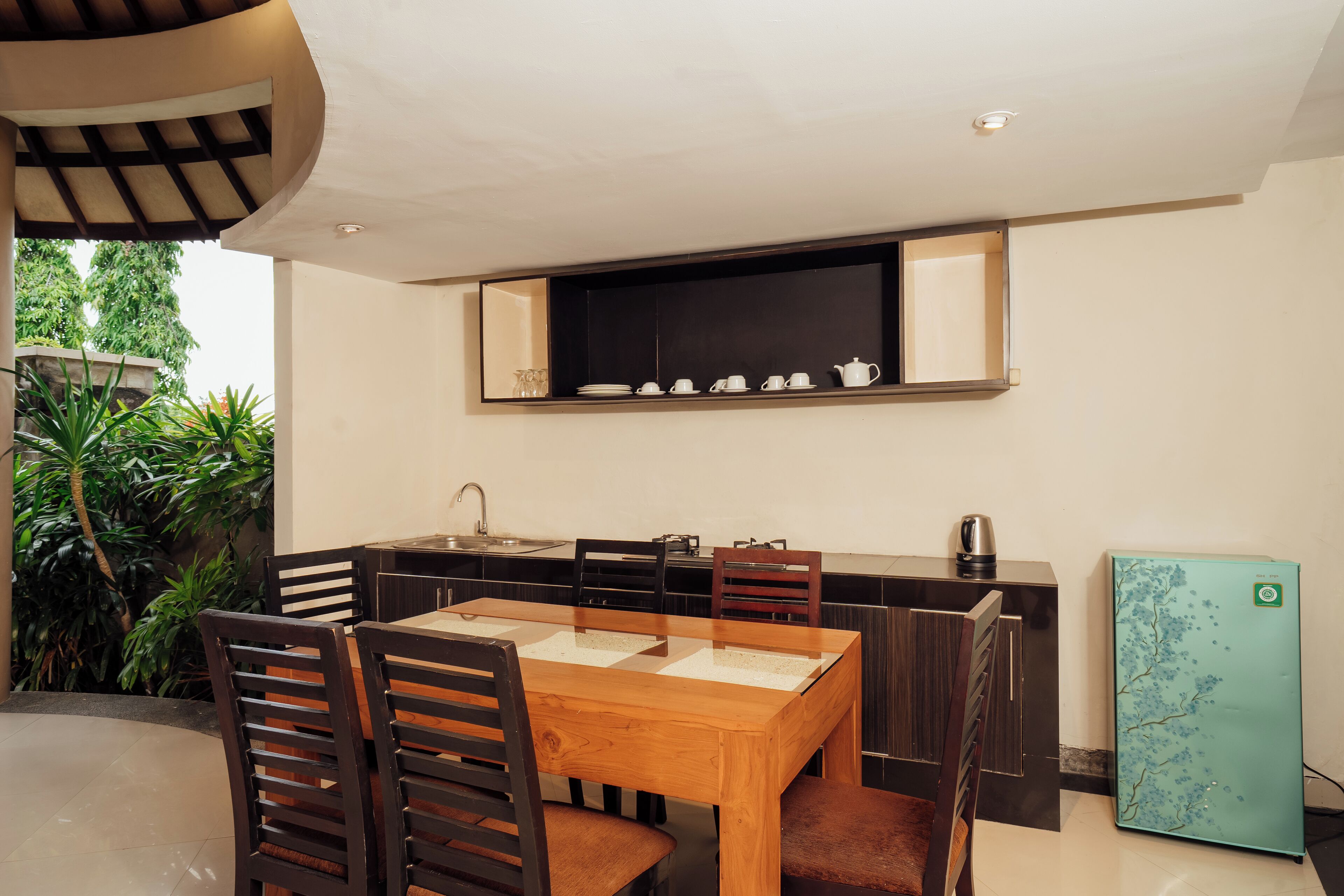 A modern kitchen with a wooden dining table, dark chairs, and a built-in refrigerator.