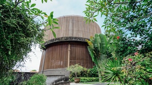A building with a cylindrical wooden structure, surrounded by lush greenery and a concrete staircase leading up to it. - The Bidadari Villas & Spa Umalas, between Seminyak and Canggu (Kerobokan)