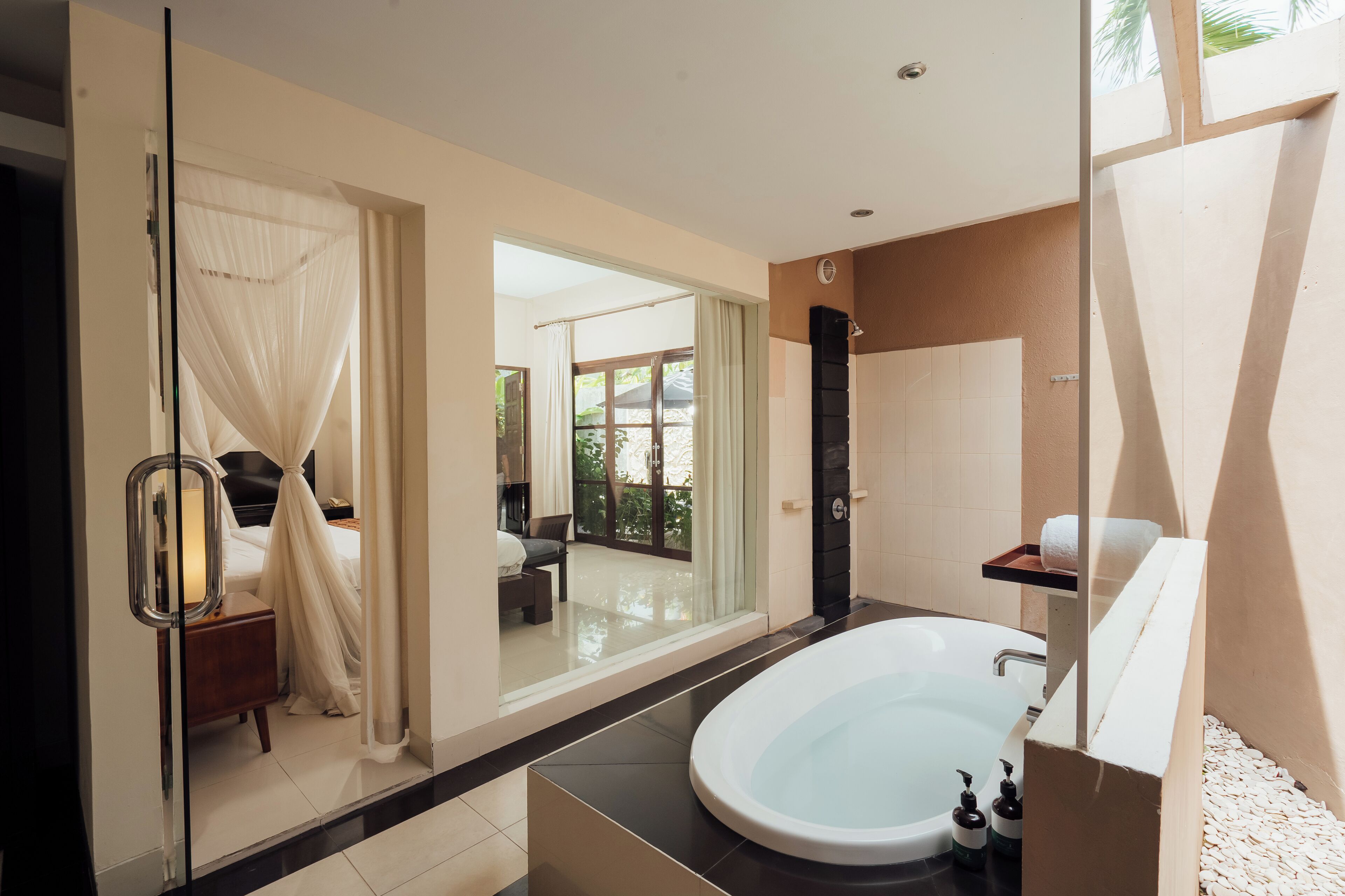 A modern bathroom with a large bathtub, a glass shower enclosure, and a view of a balcony.