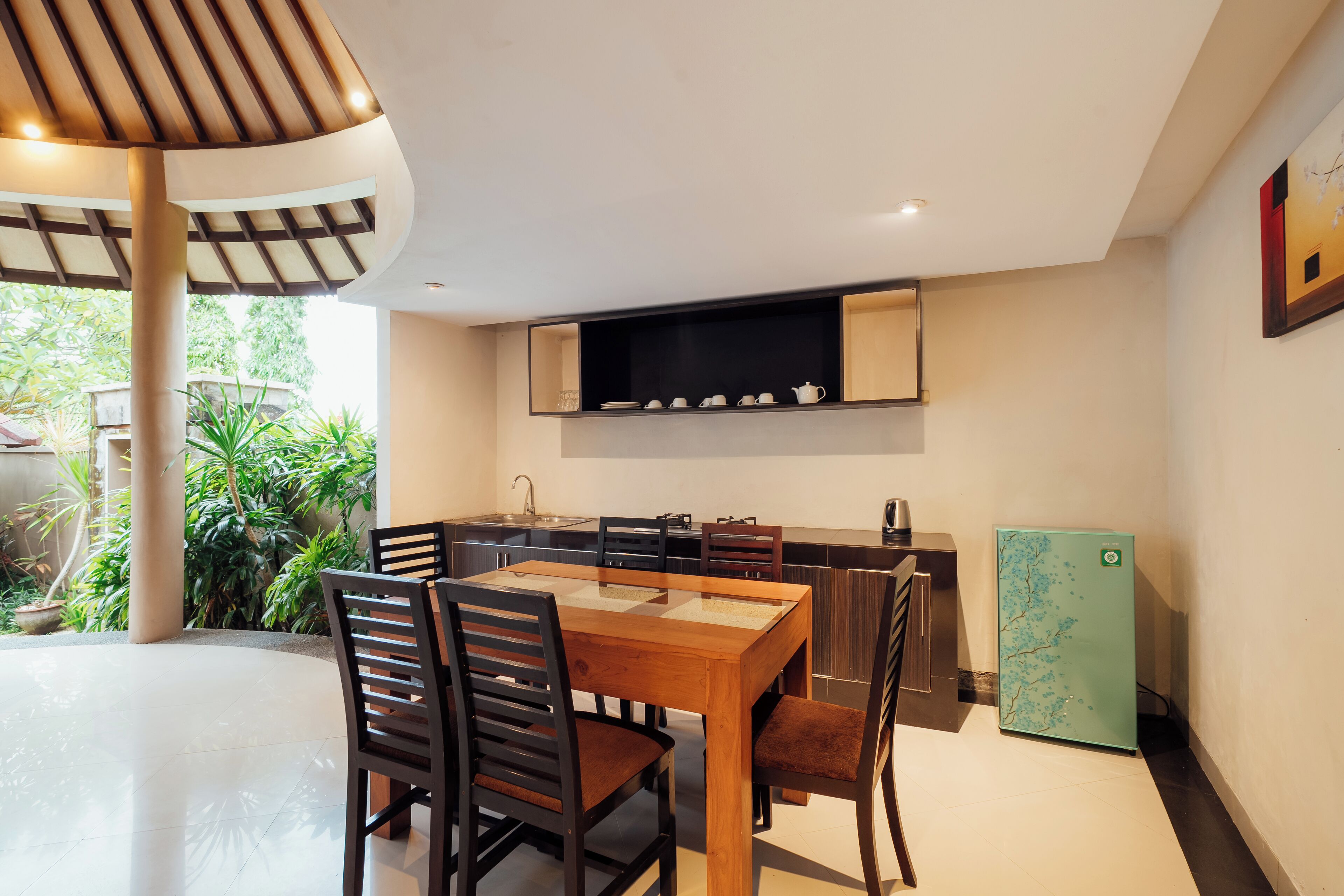 A modern kitchen with a dining area, featuring a wooden table and chairs, a built-in oven, and a refrigerator.