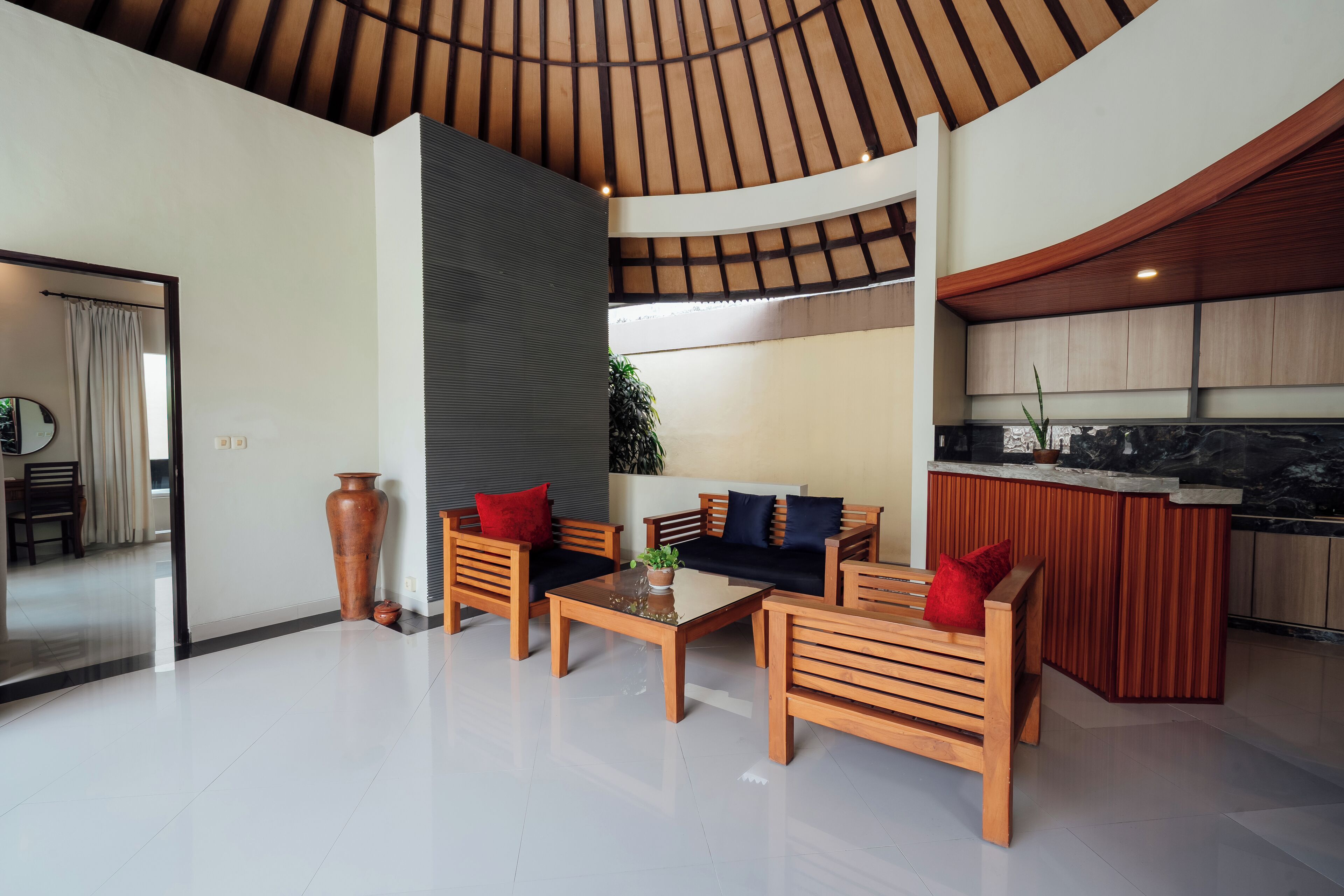 Una sala de estar moderna con una mesa de centro de vidrio, muebles de madera y una cocina con encimera de mármol.