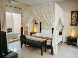 Relax in a serene space with a four-poster bed, bench, and bedside table, featuring a large mirror and TV.