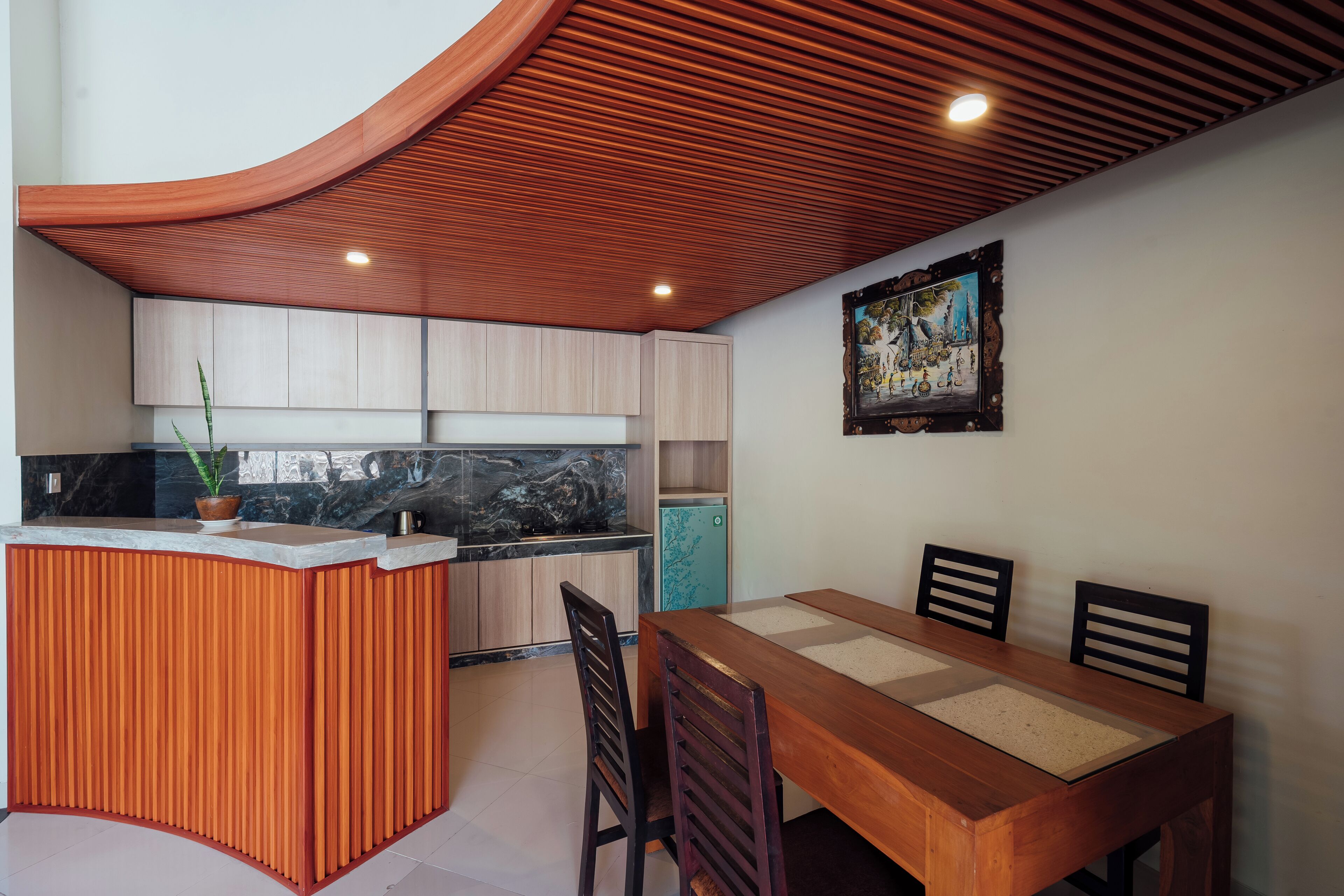 Une cuisine moderne avec un îlot central en bois, une table à manger avec des chaises et un plafond encastré.