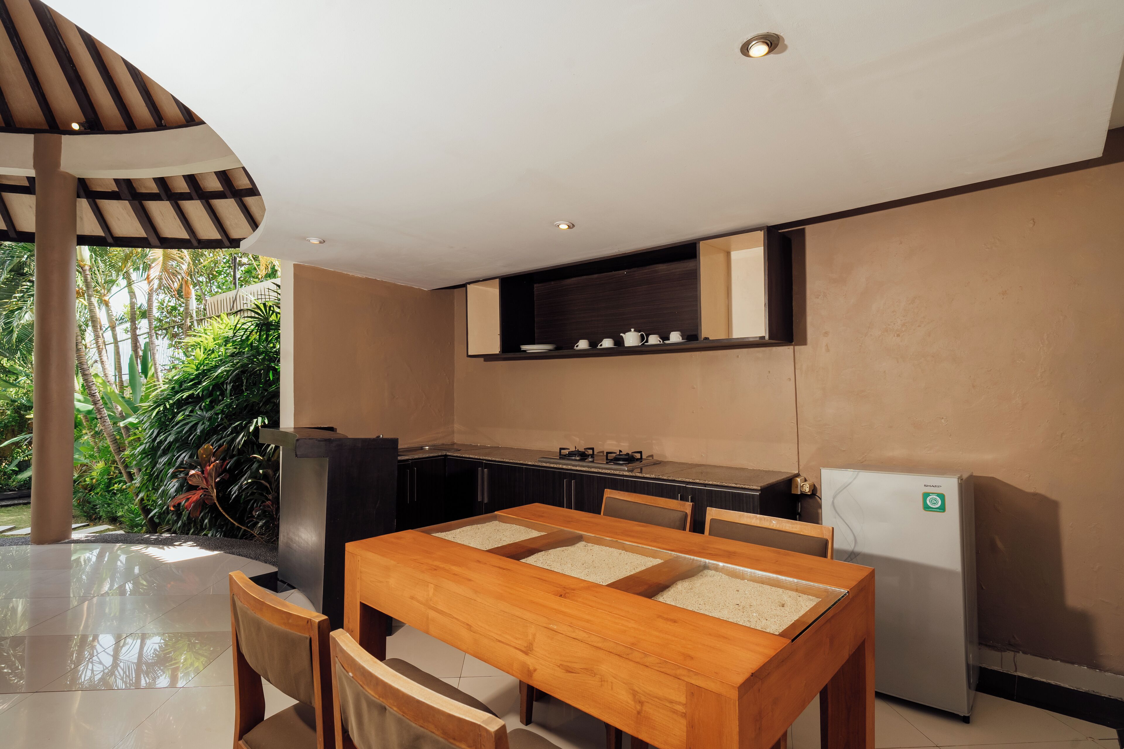 A modern kitchen with a dining area, featuring a wooden table and chairs, a built-in stove, and a refrigerator.