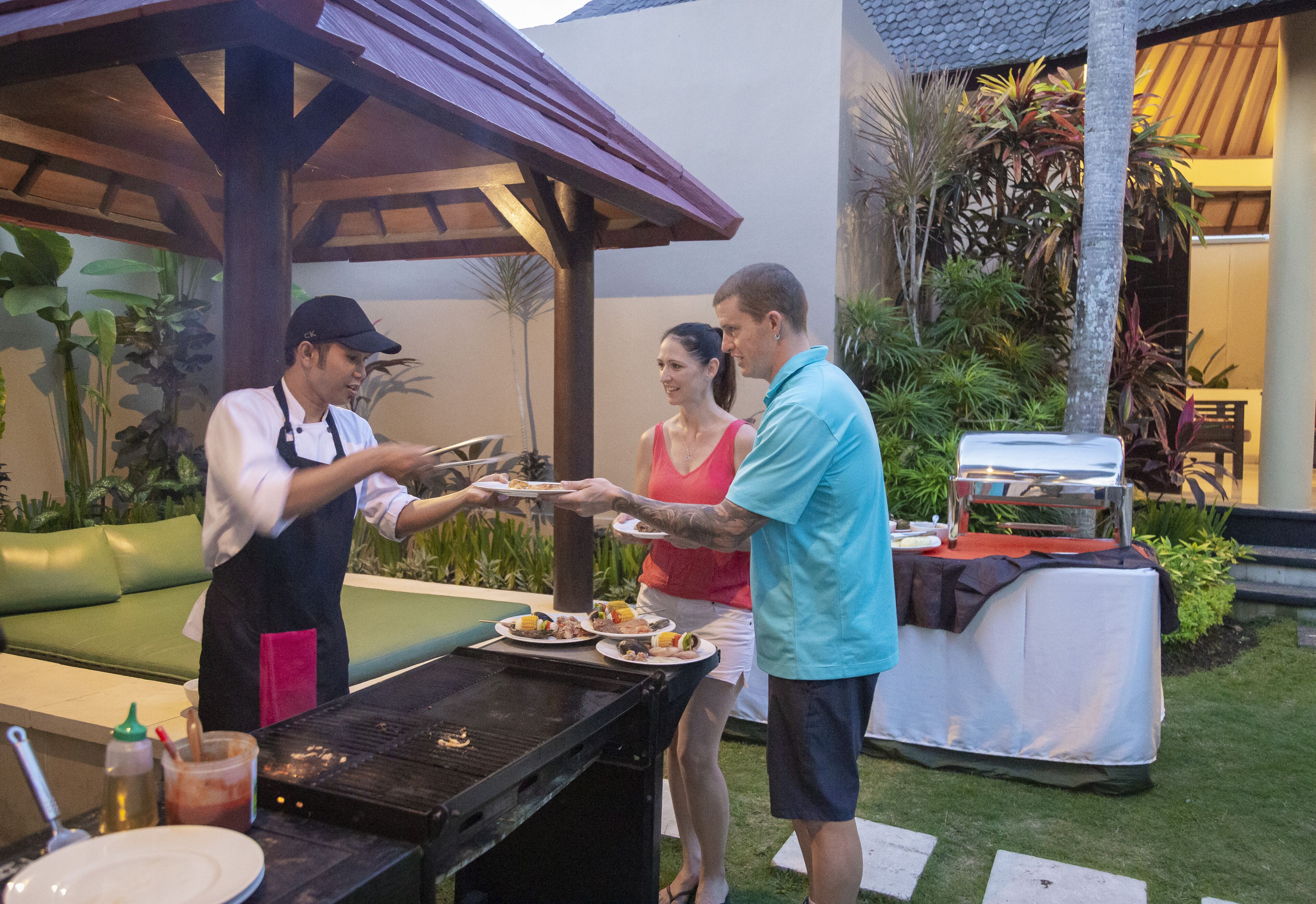 Un patio con una parrilla, mesa de comedor y una zona de estar cubierta.