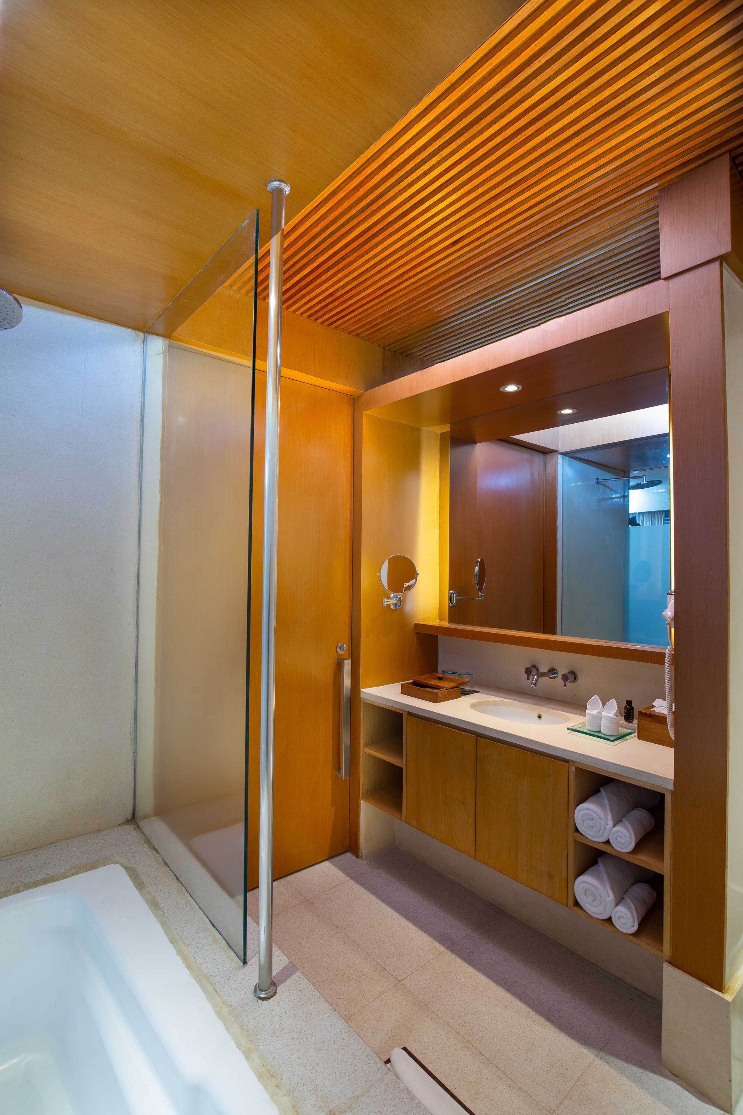 Une salle de bain moderne avec une baignoire, un grand miroir, des meubles en bois et un porte-serviettes.