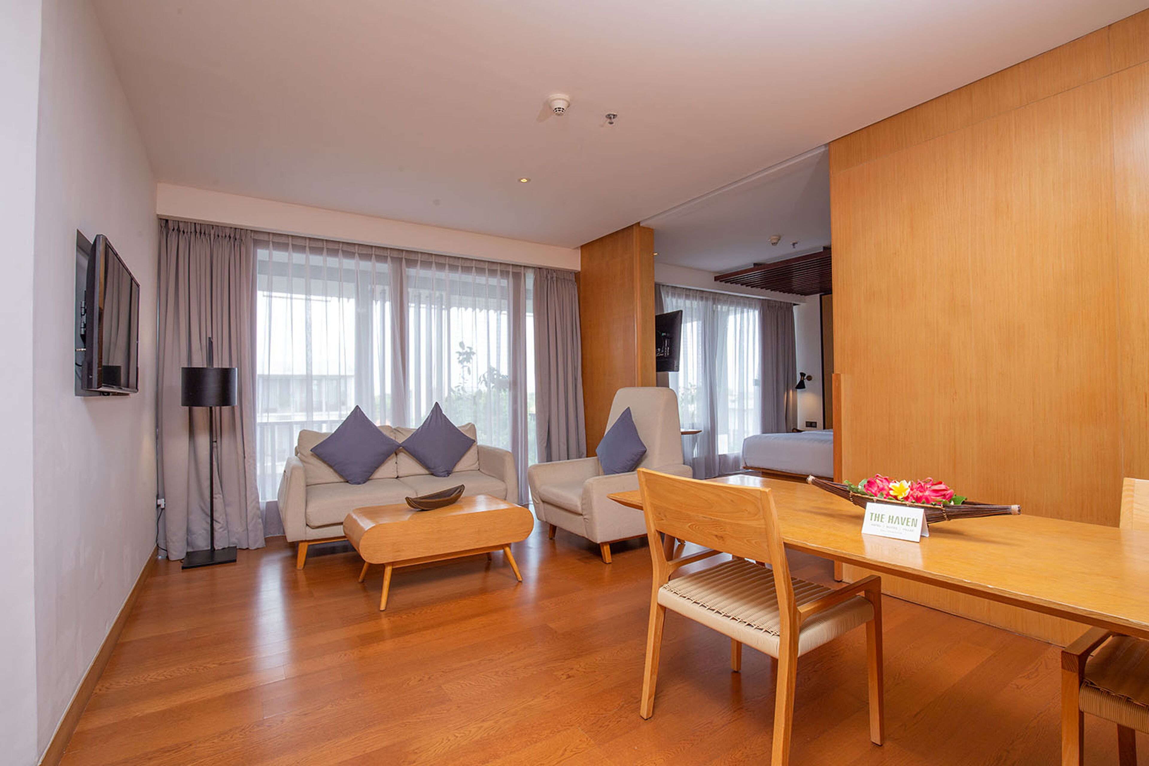 Una sala moderna con sofá, sillones, una mesa de centro de madera y una mesa de comedor con un mantel individual que dice "THE HAVEN".