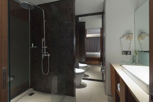 Uma casa de banho moderna com cabine de duche em vidro, sanita e toucador com espelho.