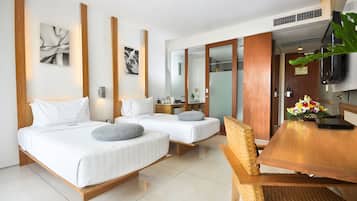 A hotel room with two beds, a wooden dining table, a television, and a mirror.
