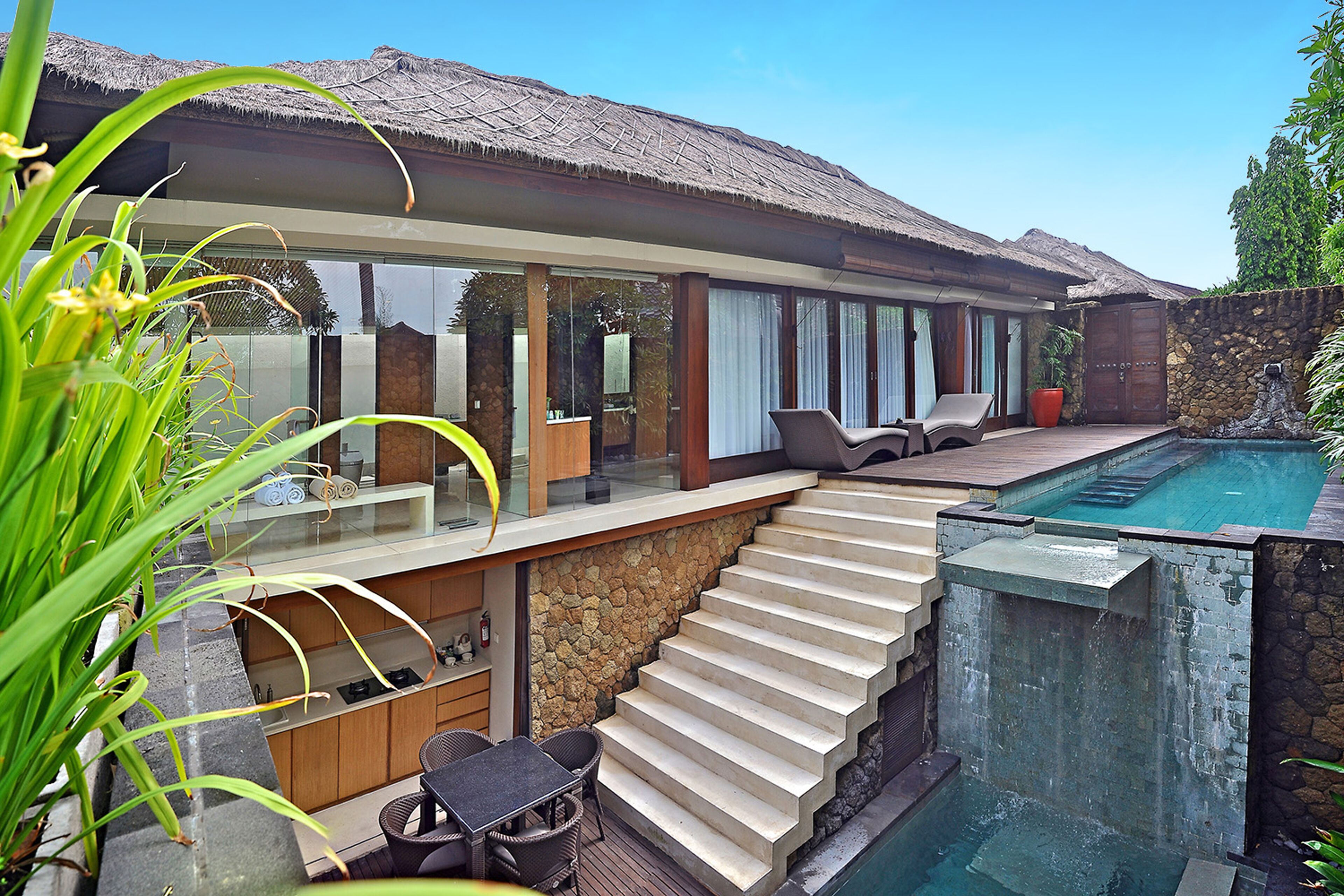 A modern house with a pool, a glass-enclosed patio, and a stone staircase.